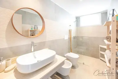 a bathroom with a sink and a mirror and a toilet at Estrella Dominicus deluxe Apartment in La Laguna