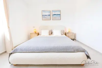 a bedroom with a white bed with two paintings on the wall at Estrella Dominicus deluxe Apartment in La Laguna