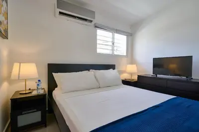 a bedroom with a white bed and a flat screen tv at Escape Studio Close to Agora Mall in Santo Domingo