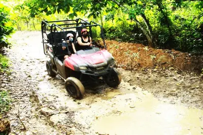 two people riding a toy car on a dirt road at Caribbean Retreat at Cana Bay Golf Residence in Punta Cana