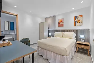 a bedroom with a bed and a desk and a kitchen at Hotel Vista Caribe Azúa in Azua de Compostela