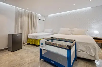 a bedroom with two beds and a table in it at Hotel Vista Caribe Azúa in Azua de Compostela
