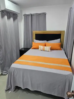 a bed with orange and white pillows in a room at hermoso apartamento céntrico in San Felipe de Puerto Plata