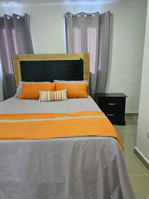 a bedroom with a bed with an orange comforter at hermoso apartamento céntrico in San Felipe de Puerto Plata