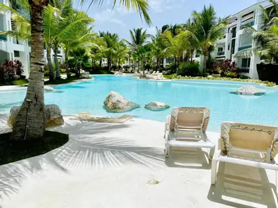 two chairs sitting next to a swimming pool with palm trees at Beautiful Star of the Caribbean - Apartment Estrella Dominicus Bayahibe in La Laguna