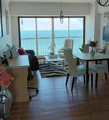 a living room with a table and a view of the ocean at Sturning Ocean View. in Santo Domingo