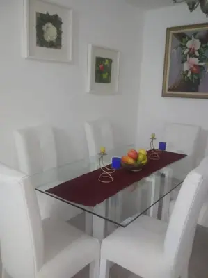 a glass table with two white chairs and a bowl of fruit at Hermoso condominio con aparcamiento gratuito in La Javilla