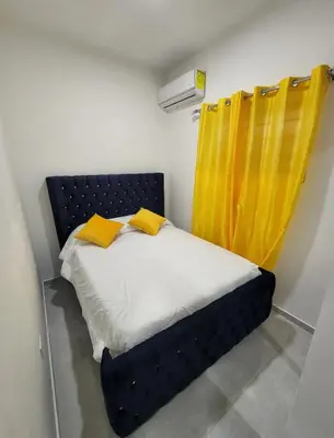 a small bedroom with a bed with yellow curtains at Umbrella Street, city Center, close to many atracctions in San Felipe de Puerto Plata