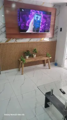 a large flat screen tv on a wall with a bench at Obynb in Santo Domingo
