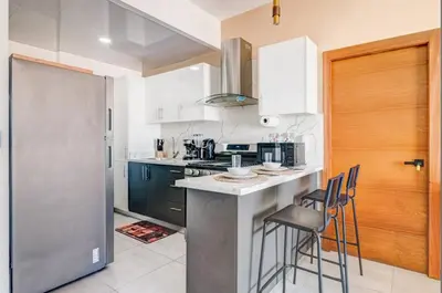 a kitchen with a counter and stools in it at Bella Vista cozy-deluxe near Downtown center in Santo Domingo