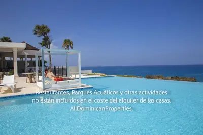 a woman sitting in a chair next to a swimming pool at Ocean Villas, Campo Del Mar in Sosúa