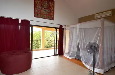 a room with a fan and curtains and a balcony at Seaside villa with housekeeping staff - Las Terrenas in Las Terrenas