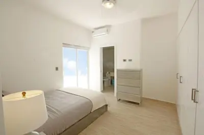 a white bedroom with a bed and a bathroom at Amplio PH de 3 hab para 9 personas in Punta Cana