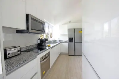 a kitchen with white cabinets and a stainless steel refrigerator at Amplio PH de 3 hab para 9 personas in Punta Cana
