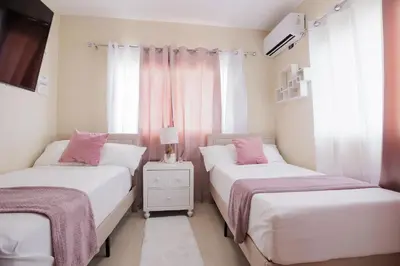 two beds in a room with pink and white at Luxury Penthouse in San Francisco de Macorís