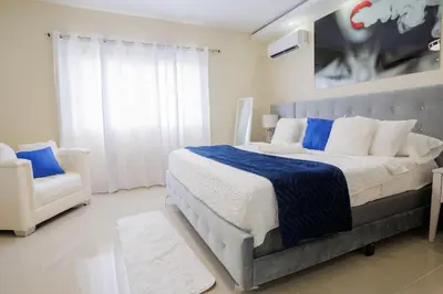 a bedroom with a large bed and a chair at Luxury Penthouse in San Francisco de Macorís