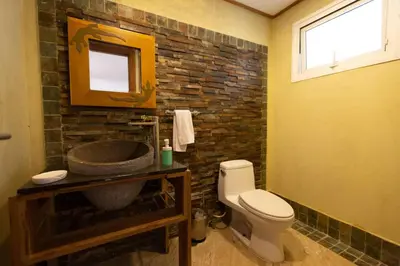 a bathroom with a toilet and a stone wall at Balcones Del Atlantic Beachfrontbbq in Las Terrenas