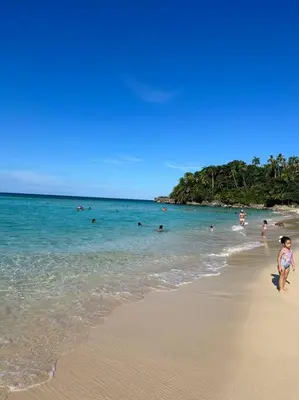 a young girl walking on a beach with people in the water at Casita Yanella in Cabrera