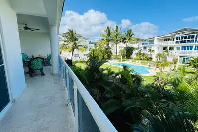 a balcony with a view of a pool and palm trees at La Fenice Beachfront with King Beds in Las Terrenas