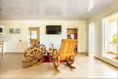 a living room with two wooden chairs and a wooden wagon at Casa Mami in Río San Juan