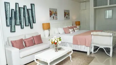 a white bedroom with a bed and a couch at Guacamayos Hotel in Bonao