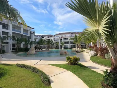 a resort swimming pool with palm trees and buildings at Acogedor apartamento en Estrella Dominicus in La Laguna