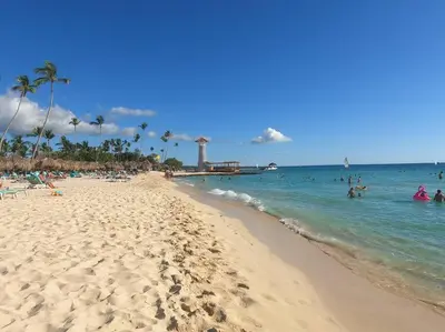 a beach with people in the water and a pier at Acogedor apartamento en Estrella Dominicus in La Laguna