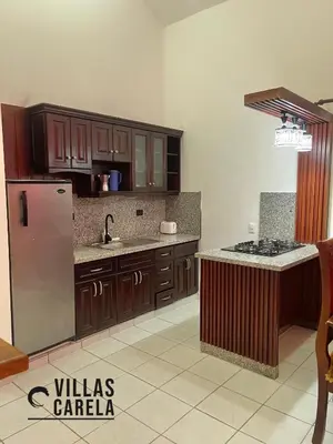 a kitchen with wooden cabinets and a stainless steel refrigerator at Villas Carela in Cabarete
