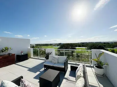 a patio with a couch and chairs on a balcony at Cana Pearl Penthouse, Hard Rock Golf & Casino in Punta Cana