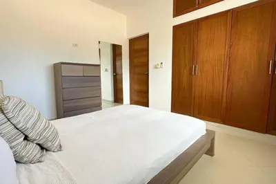 a bedroom with a white bed and wooden cabinets at La Fenice Beachfront 3 Bedroom With Parking in Las Terrenas