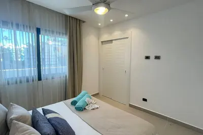 a bedroom with a bed with blue pillows and a window at Tropical Caribbean space with 2 bedrooms C3 in Punta Cana