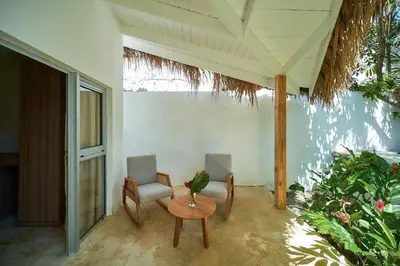 a porch with two chairs and a table with a bird on it at Empyrean Tropical Wellness Portillo in Las Terrenas