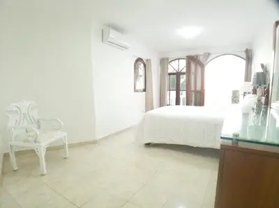 a white bedroom with a bed and a chair at Immaculate 1-Bed Apartment in Cofresi in Las Flores