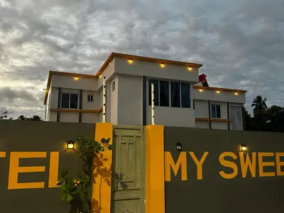 a house behind a fence with a green door at Hotel Mi Dulce Amanecer PyR in Nagua