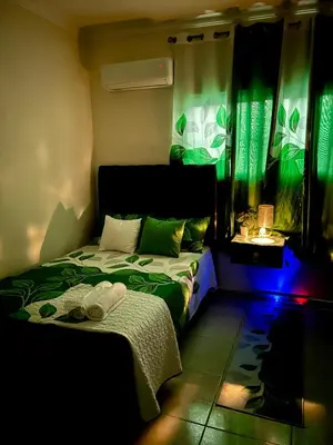 a bedroom with two beds and a window with green curtains at Hotel Mi Dulce Amanecer PyR in Nagua