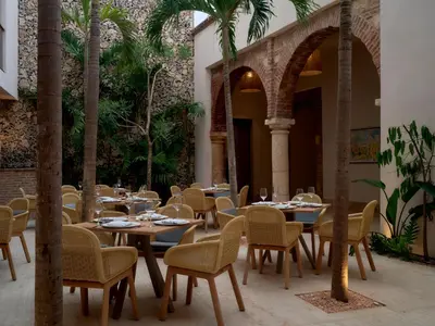 a restaurant with tables and chairs and palm trees at Kimpton Las Mercedes by IHG in Santo Domingo