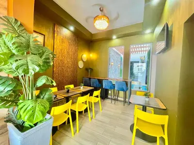 a restaurant with yellow chairs and tables and a plant at RIG Puerto Malecón in Santo Domingo