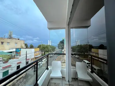 a balcony with white chairs and a view of a city at RIG Puerto Malecón in Santo Domingo