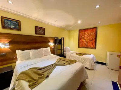 two beds in a hotel room with yellow walls at RIG Puerto Malecón in Santo Domingo