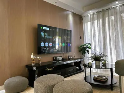 a living room with a flat screen tv and chairs at Apartamento Riviera Colonial, Santo Domingo in Calero