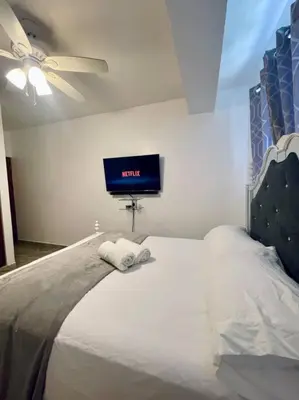 a bedroom with a bed with a tv on the wall at Super Cozy n´Confortable apart. in Ensanche Los Minas