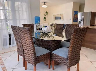 a dining room with a glass table and wicker chairs at Acogedor Apartamento remodelado in Sosúa