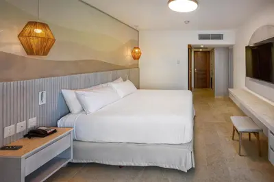 a bedroom with a large white bed and a television at Viva Miches by Wyndham, a Trademark All Inclusive Resort in Miches