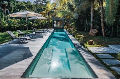 a swimming pool with two chairs and an umbrella at Casa Ataraxia Modern Luxe Villa in Las Terrenas