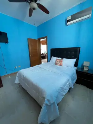 a blue bedroom with a bed with a ceiling fan at Bello Apartamento en Santiago con todas las comodidades in Santiago de los Caballeros