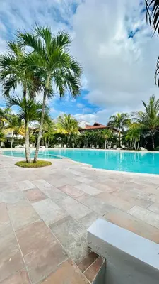 a pool with a palm tree and a bench at Bayahibe Paraíso in Bayahibe