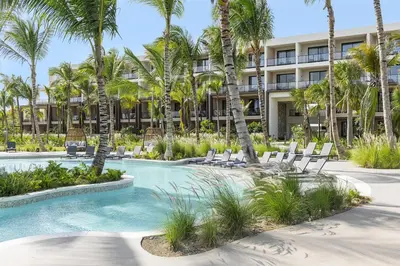 a resort with a swimming pool with chairs and palm trees at Zemi Miches Punta Cana All-Inclusive Resort, Curio by Hilton in Miches