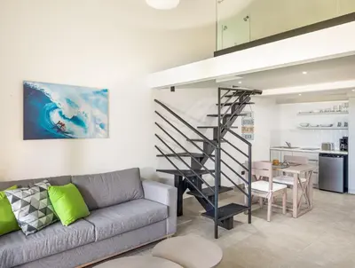 a living room with a couch and a spiral staircase at Kite Beach Penthouse in Cabarete