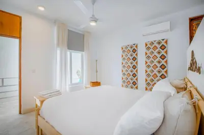 a white bedroom with a large bed and a window at Enriquillo 2-Bedroom Apt Casa Areito in Santo Domingo