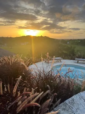 a person sitting on a bench in front of a sunset at Margarita Ecovillage in Miches